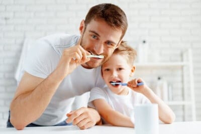 father and son brushing teeth together