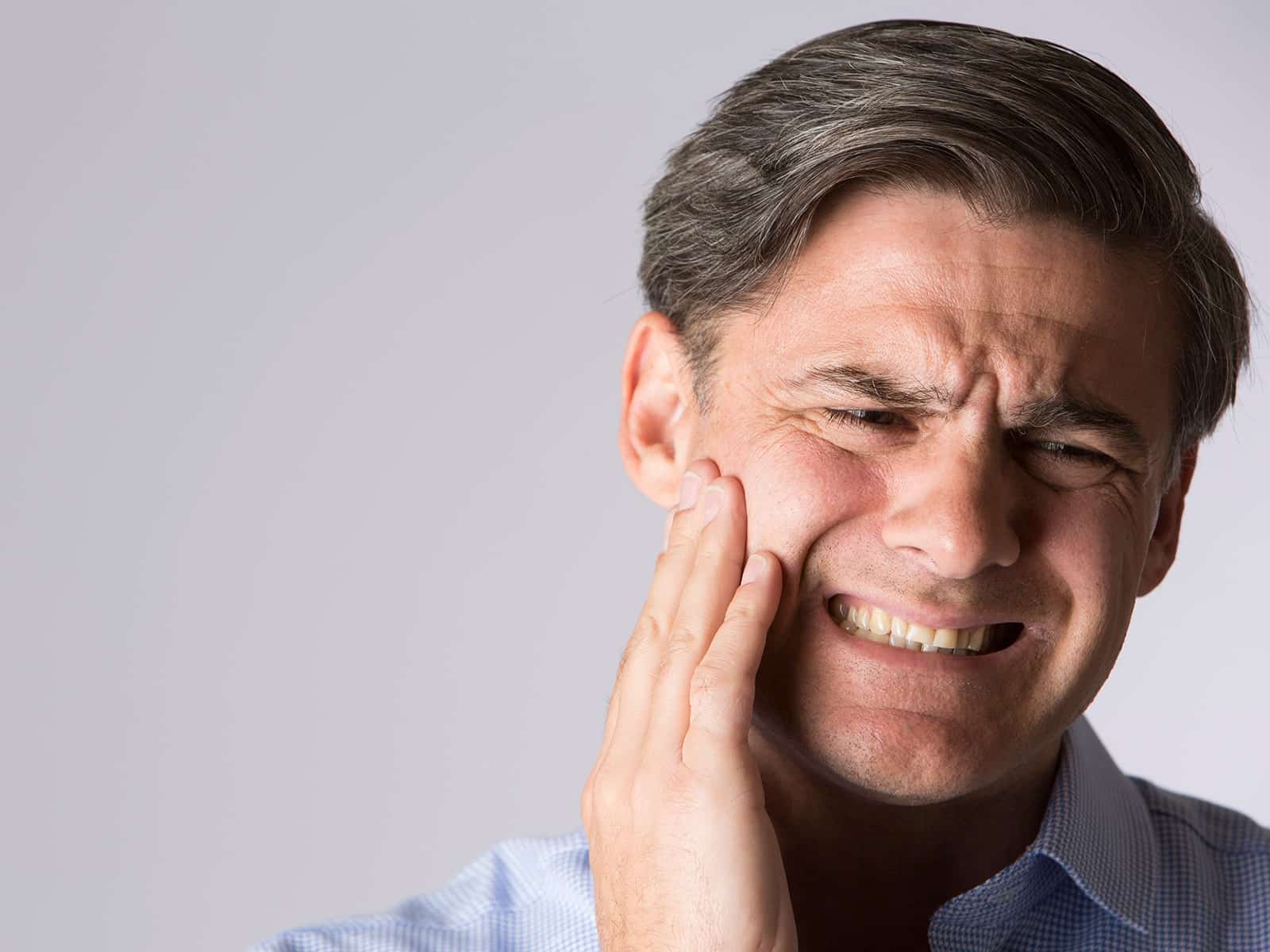 Man experiencing tooth pain and holding his cheek